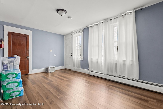 empty room featuring hardwood / wood-style flooring and a baseboard heating unit