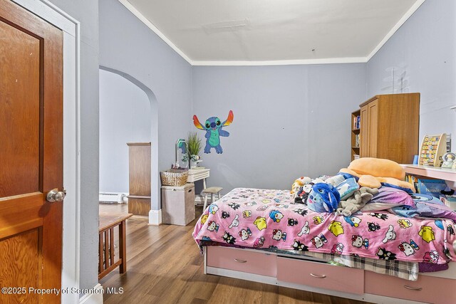 bedroom with hardwood / wood-style floors, baseboard heating, and ornamental molding