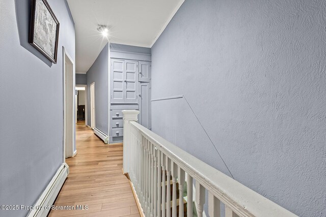 hallway featuring crown molding, a baseboard radiator, and light wood-type flooring