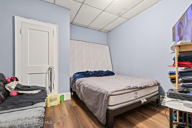 bedroom with wood-type flooring and a drop ceiling