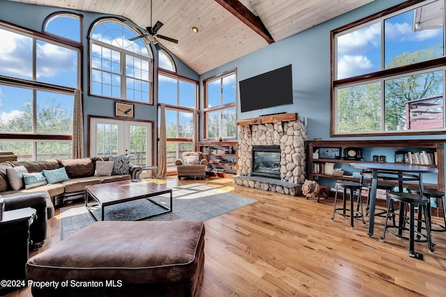 living room with a high ceiling, light hardwood / wood-style flooring, and beam ceiling