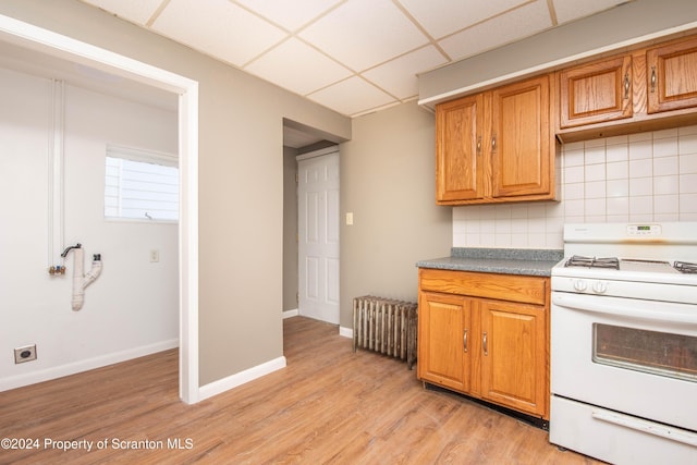 kitchen with a drop ceiling, radiator, light hardwood / wood-style flooring, tasteful backsplash, and white range oven