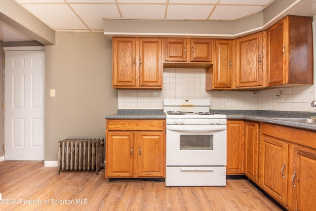 kitchen featuring tasteful backsplash, radiator, a drop ceiling, and white range