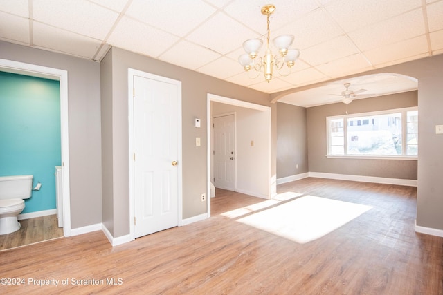 unfurnished room featuring ceiling fan with notable chandelier, wood-type flooring, and a paneled ceiling