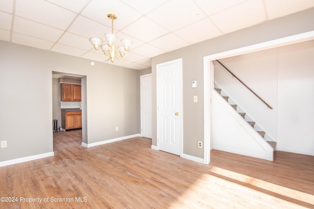 unfurnished room featuring a paneled ceiling, hardwood / wood-style floors, and a chandelier