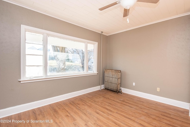 unfurnished room with radiator heating unit, hardwood / wood-style flooring, plenty of natural light, and crown molding