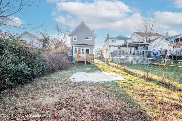 back of property with a lawn and a wooden deck