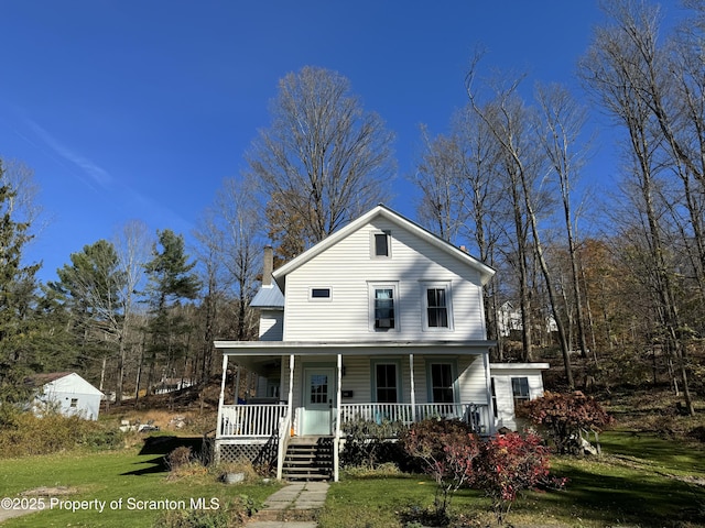 view of front facade featuring covered porch, a chimney, metal roof, and a front yard