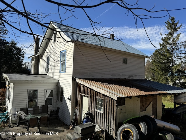 exterior space featuring metal roof, a chimney, and a patio