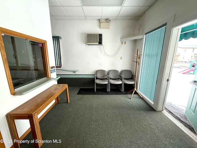 misc room with a paneled ceiling, dark carpet, and a wall mounted air conditioner