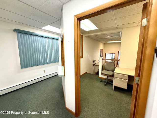 hallway with a paneled ceiling, dark carpet, and a baseboard radiator