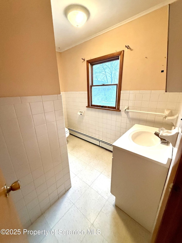 bathroom featuring a baseboard radiator, vanity, tile walls, toilet, and crown molding