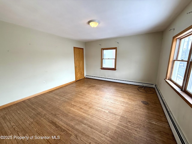 spare room with a healthy amount of sunlight, wood-type flooring, and a baseboard radiator