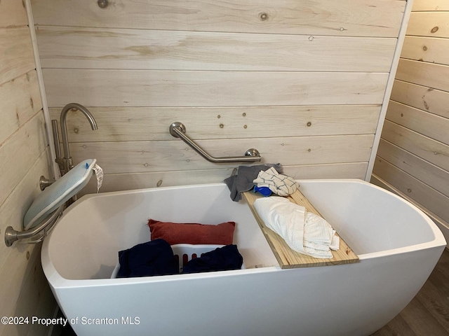 bathroom featuring a tub to relax in and wooden walls