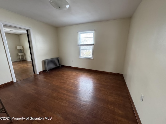 unfurnished room with dark hardwood / wood-style floors and radiator