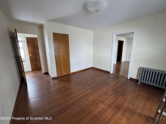 spare room with radiator heating unit and dark wood-type flooring