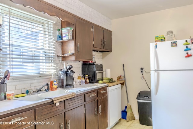 kitchen featuring backsplash, dark brown cabinetry, sink, and white appliances