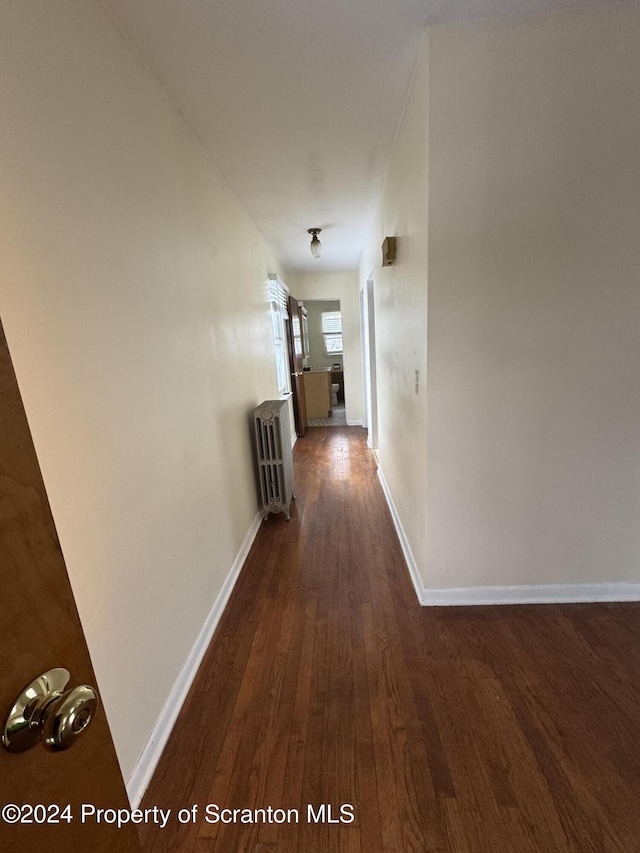 corridor with dark hardwood / wood-style floors and radiator