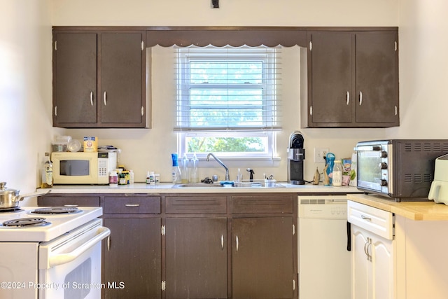 kitchen with dark brown cabinets, white appliances, and sink