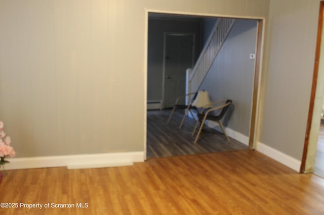spare room with baseboards, a baseboard radiator, stairs, and wood finished floors