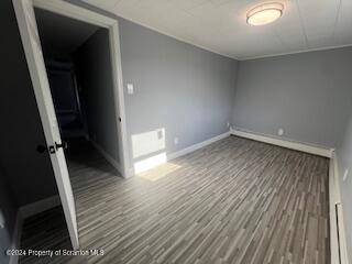 empty room with hardwood / wood-style floors and a baseboard radiator