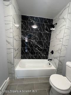 bathroom featuring toilet, tiled shower / bath, and tile walls