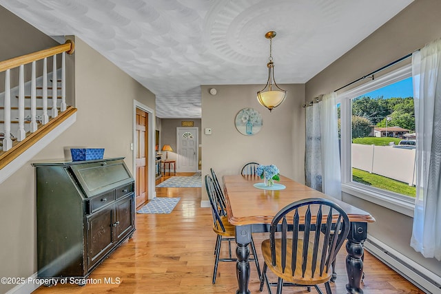 132 6th St, Blakely, PA 18447 - dining area with a baseboard heating unit, light wood-style floors, and stairs