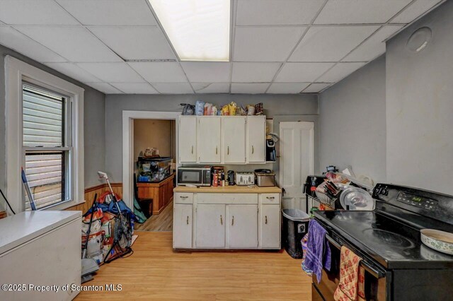 1014 Jackson St 1012, Scranton, PA 18504 - kitchen featuring black / electric stove, stainless steel microwave, a paneled ceiling, light wood-style floors, and white cabinets