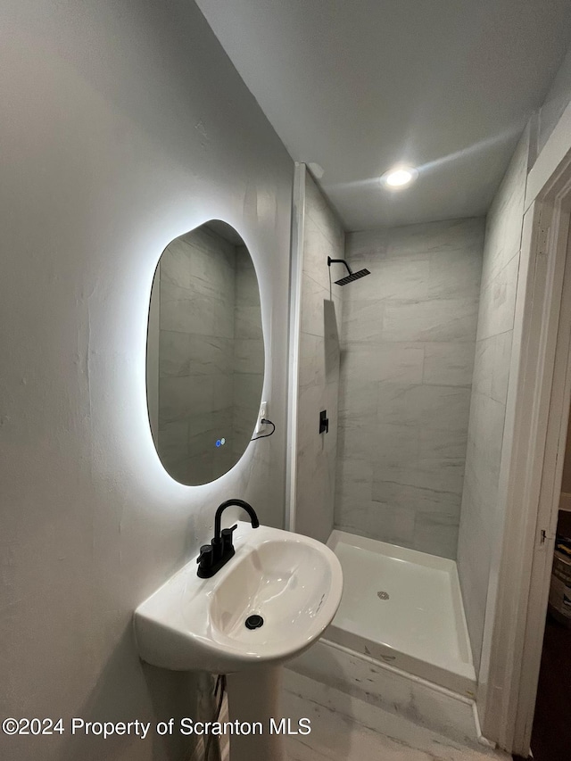 bathroom with a tile shower and sink