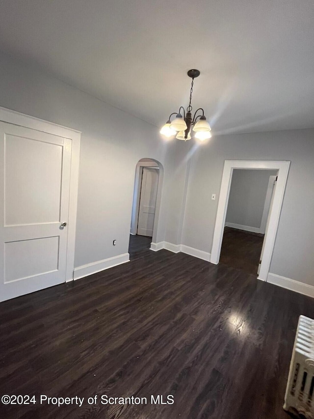 unfurnished living room with dark wood-type flooring and an inviting chandelier