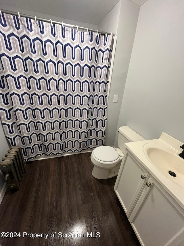 bathroom with vanity, hardwood / wood-style flooring, toilet, curtained shower, and radiator heating unit