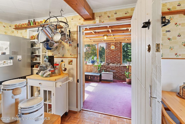 kitchen with stainless steel fridge, beam ceiling, ornamental molding, and light parquet floors