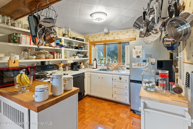 kitchen with kitchen peninsula, light parquet floors, sink, black appliances, and white cabinetry