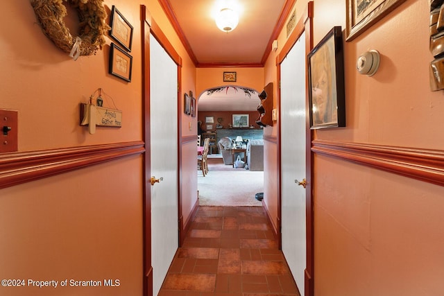 hallway with dark colored carpet and crown molding