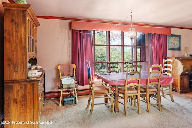 carpeted dining area with crown molding