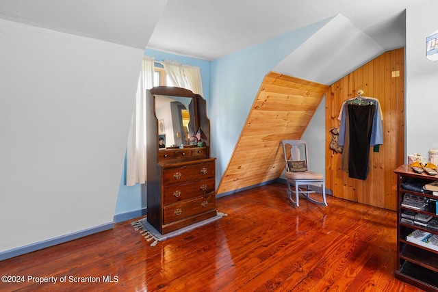 bedroom with hardwood / wood-style flooring, vaulted ceiling, and wood walls