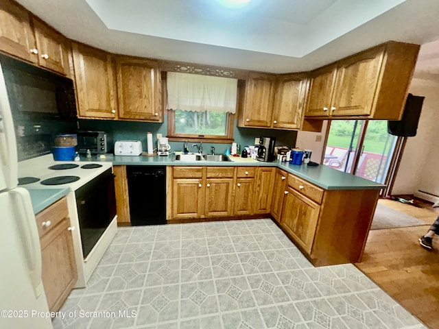 13 Mundro Rd, Scott Twp, PA 18447 - kitchen with black appliances, a peninsula, brown cabinetry, a tray ceiling, and light countertops