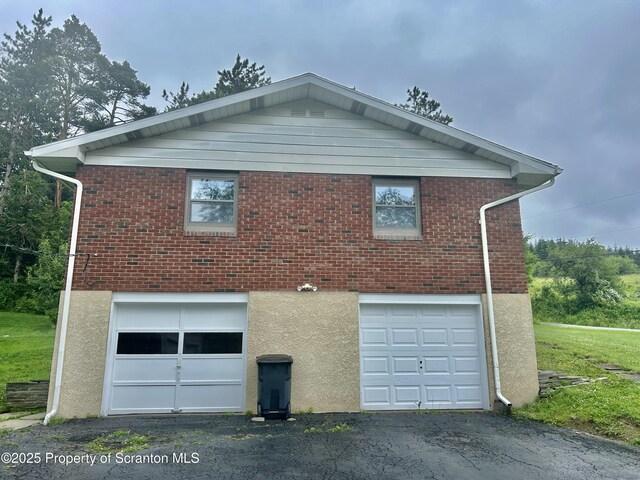 13 Mundro Rd, Scott Twp, PA 18447 - view of property exterior with an attached garage, driveway, stucco siding, and brick siding