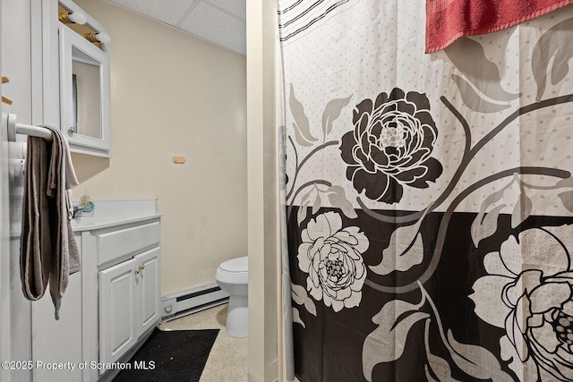 bathroom with a drop ceiling, toilet, vanity, and a baseboard radiator