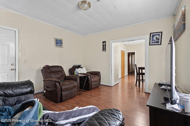 living room featuring ornamental molding, wood finished floors, and baseboards