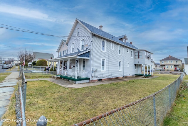 view of side of home with a fenced backyard, covered porch, a shingled roof, a lawn, and a chimney