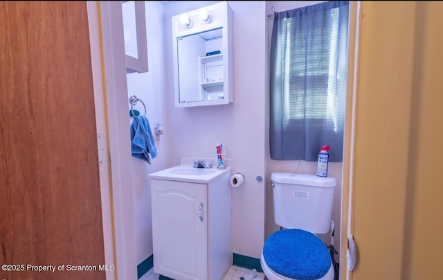 half bathroom featuring vanity, toilet, and baseboards