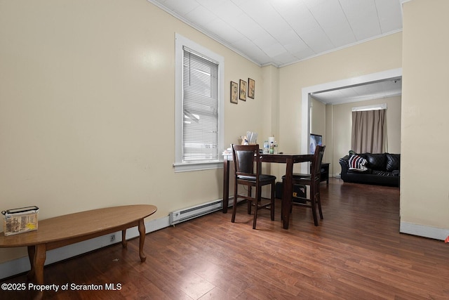 dining space with ornamental molding, baseboard heating, wood finished floors, and baseboards