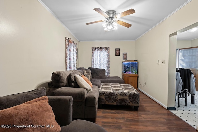 living area with ornamental molding, ceiling fan, baseboards, and wood finished floors