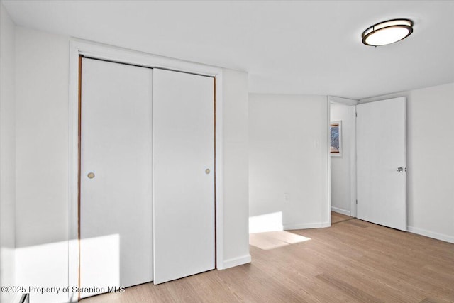 unfurnished bedroom with wood finished floors, a closet, and baseboards