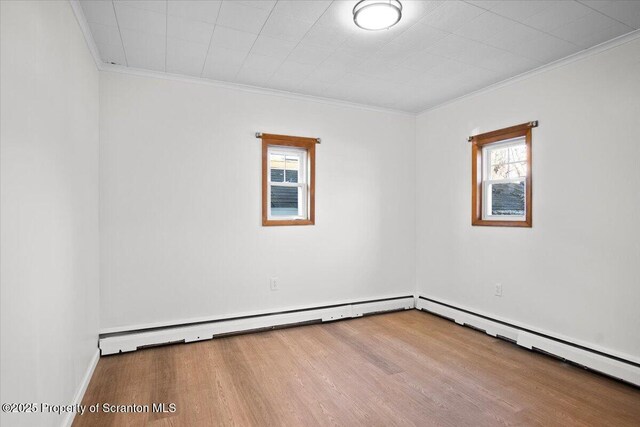 spare room with a wealth of natural light, a baseboard radiator, crown molding, and wood finished floors