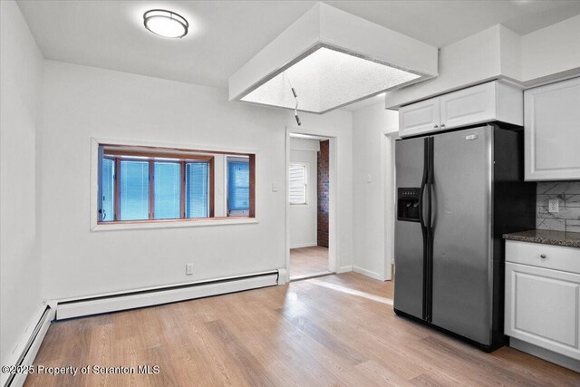 kitchen with light wood-type flooring, stainless steel fridge, baseboard heating, and white cabinetry
