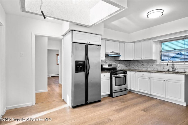 kitchen featuring a baseboard radiator, a sink, stainless steel appliances, white cabinets, and under cabinet range hood