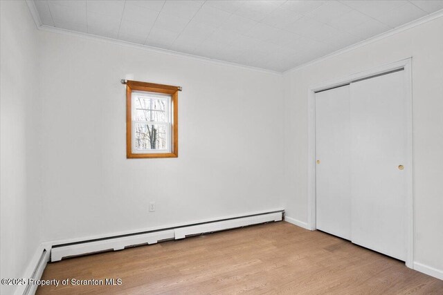 unfurnished bedroom with crown molding, wood finished floors, and baseboard heating