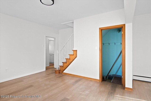 unfurnished living room with stairway, wood finished floors, and baseboards